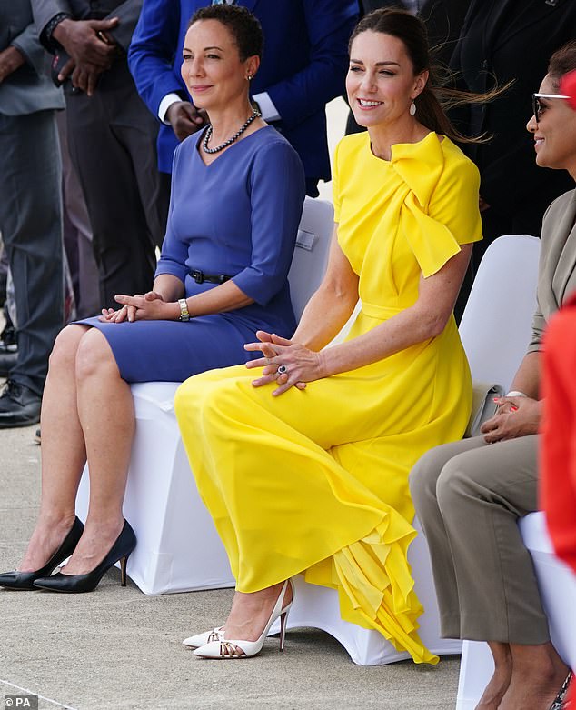 Die dreifache Mutter zeigte in der gelben Robe einmal mehr ihre Leidenschaft für Diplomatenuniformen, als sie das Statement-Piece mit weißen Aquazzura-Stöckelschuhen mit goldgestreiften Ausschnitten kombinierte.