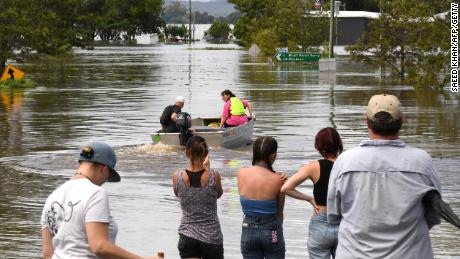 Anwohner stehen am 1. März 2022 neben einer überfluteten Straße im Vorort Lawrence, etwa 70 Kilometer von der Grenzstadt Lismore in New South Wales entfernt. 