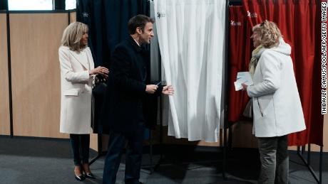Der französische Präsident Emmanuel Macron (Mitte) spricht neben seiner Frau Brigitte Macron (links) mit einem Einwohner, bevor er am Sonntag über die erste Runde der Präsidentschaftswahl abstimmt.