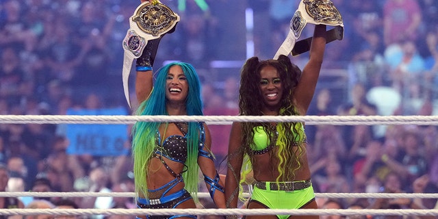 3. April 2022;  Arlington, Texas, USA;  Sasha Banks (links) und Naomi feiern nach einem fatalen Vierkampf in der Women's Tag Team Championship während WrestleMania in der AT&T Arena  T.