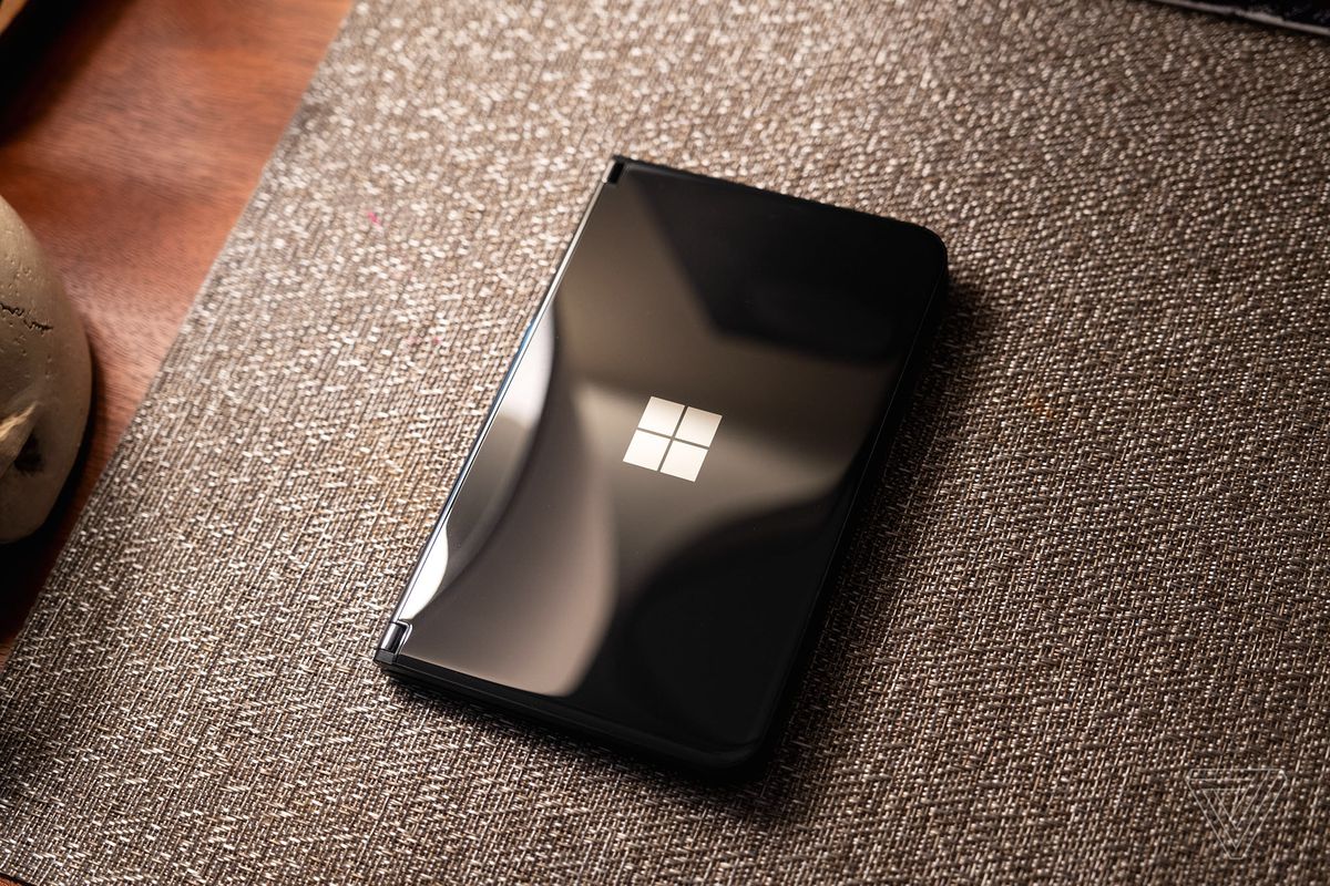 Microsoft Surface Duo 2 schwarz geschlossen und auf einer Matratze sitzend.