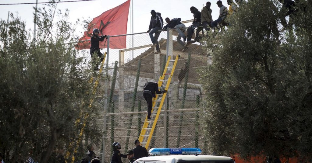 Dutzende Migranten drängen sich am Grenzzaun in Melilla