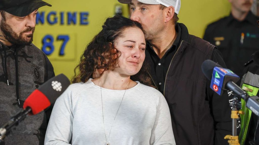 Paramedic Jayme Erickson, center, who was called to a crash last week and didn't know she was trying to save her own daughter because the injuries were too severe, is comforted by her husband Sean Erickson, as she speaks to the media in Airdrie, Alberta, Tuesday.
