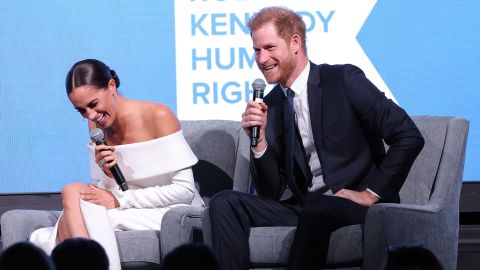 Das Paar lacht, als sie sich während der Veranstaltung auf der Bühne mit Kerry Kennedy unterhalten. 